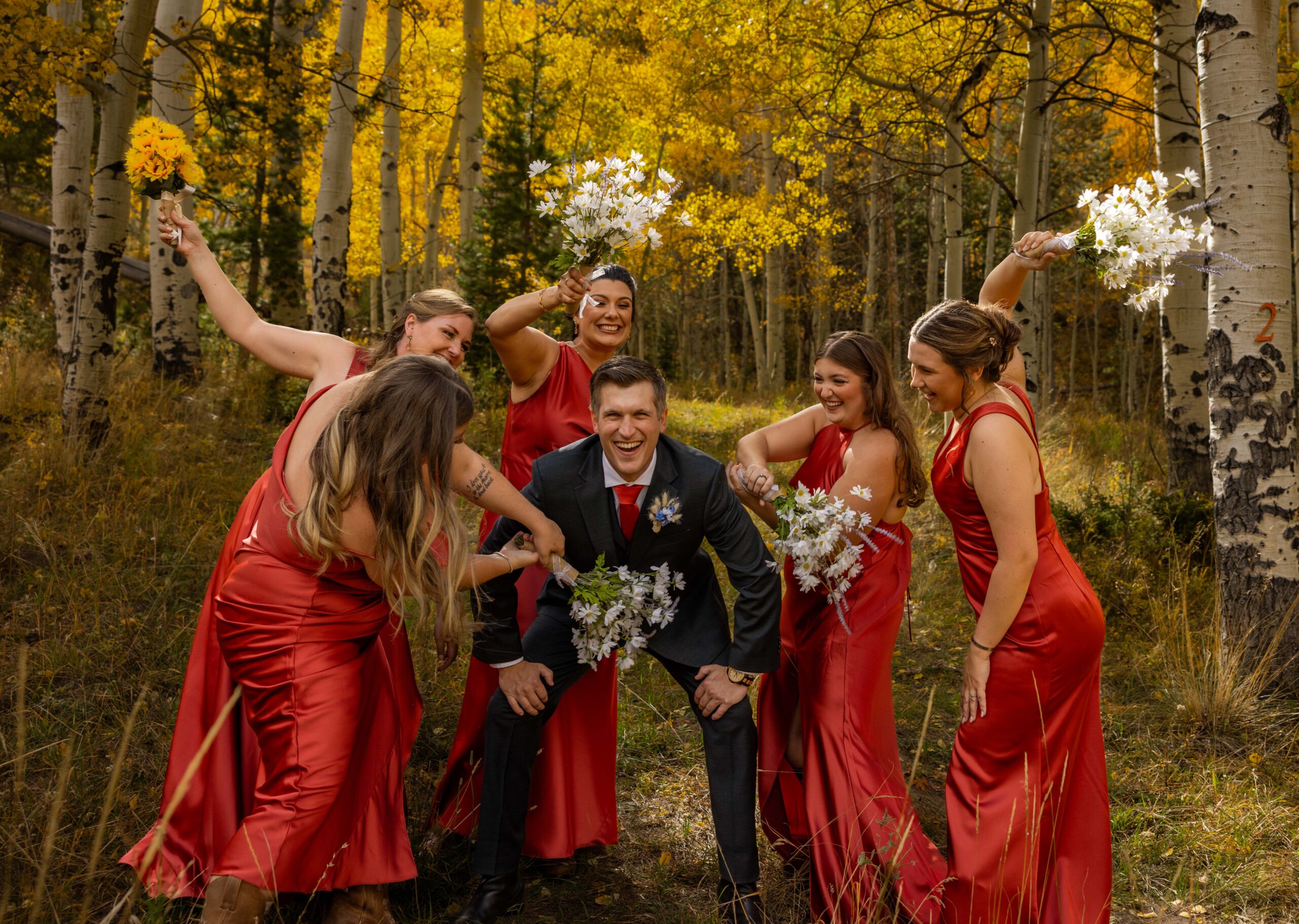 bridal party taking picture with the groom for a wedding in fall time in colorado with yellow aspen trees